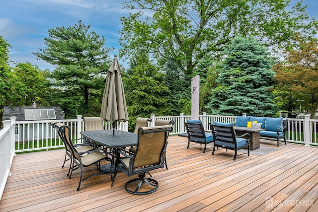 wooden deck with outdoor dining area, outdoor lounge area, view of wooded area, and an outdoor structure