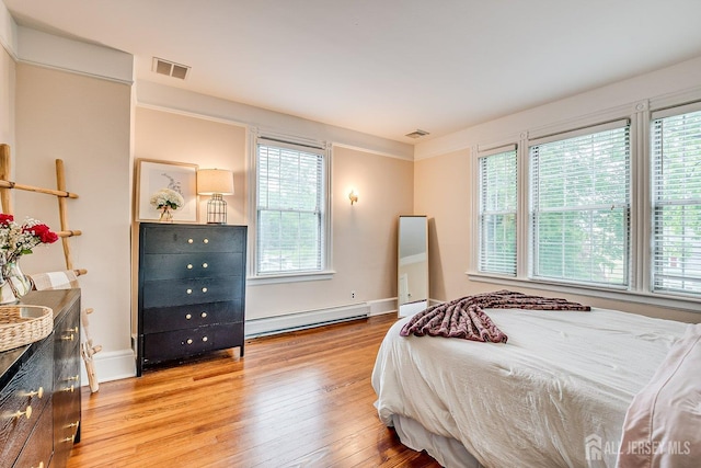 bedroom featuring baseboard heating, light wood-style floors, and baseboards