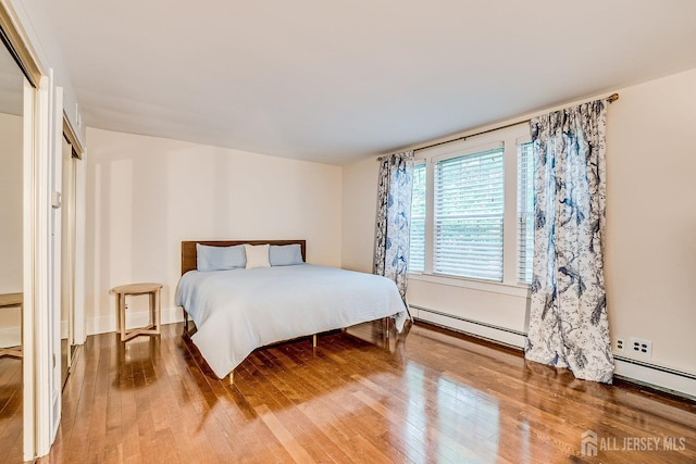 bedroom featuring a baseboard radiator and hardwood / wood-style flooring