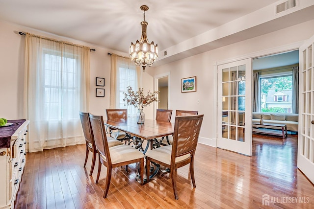 dining area with a chandelier, light wood finished floors, french doors, and baseboards