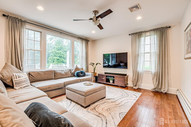 living room with baseboard heating, ceiling fan, healthy amount of natural light, wood-type flooring, and recessed lighting