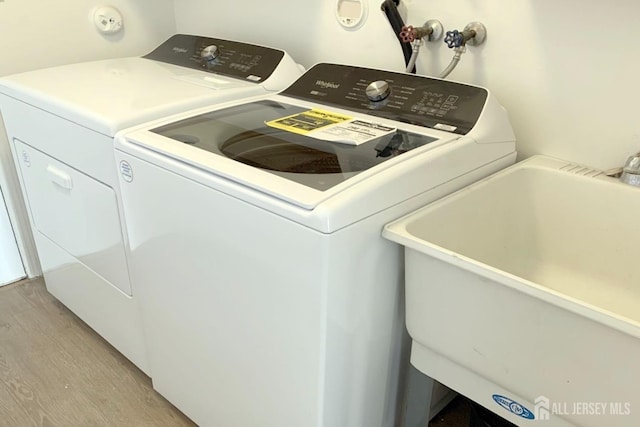 laundry area with light wood-style floors, washing machine and dryer, laundry area, and a sink