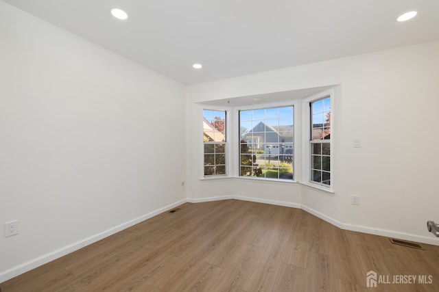 spare room with light wood-type flooring, visible vents, baseboards, and recessed lighting