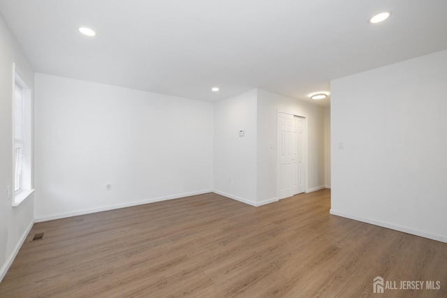 spare room featuring light wood-type flooring, visible vents, baseboards, and recessed lighting