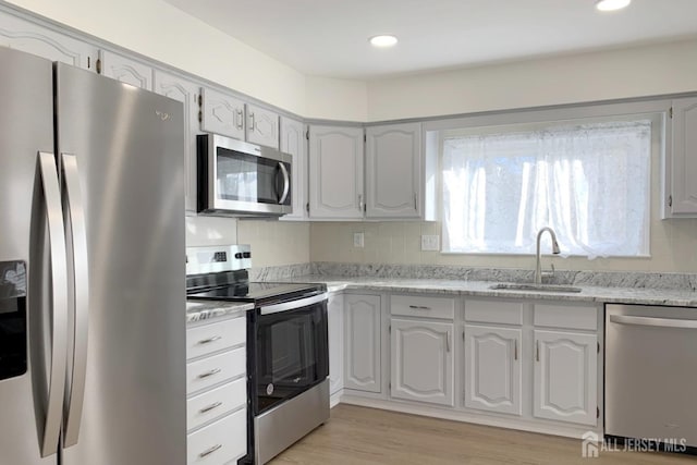 kitchen with appliances with stainless steel finishes, recessed lighting, a sink, and light wood-style floors