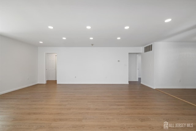 empty room featuring baseboards, light wood finished floors, visible vents, and recessed lighting