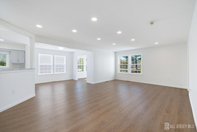 unfurnished living room featuring baseboards, wood finished floors, and recessed lighting