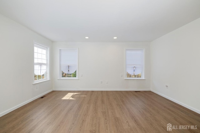 empty room with recessed lighting, baseboards, visible vents, and light wood finished floors