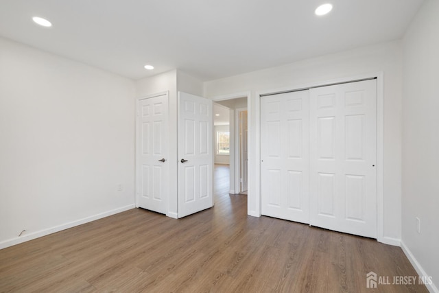 unfurnished bedroom with baseboards, wood finished floors, and recessed lighting