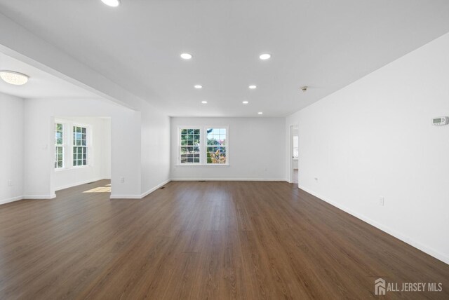 unfurnished living room featuring a wealth of natural light and dark wood-type flooring