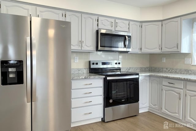 kitchen with stainless steel appliances, backsplash, white cabinetry, and light wood-style flooring