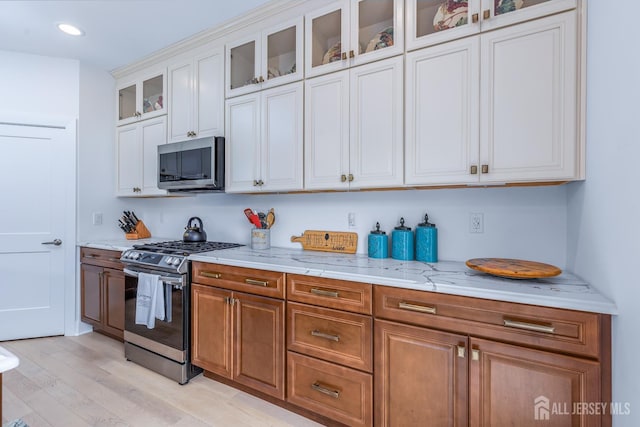 85 Valentino Dr, Old Bridge, NJ 08875 - kitchen with stainless steel appliances, light stone countertops, light wood-type flooring, white cabinetry, and glass insert cabinets