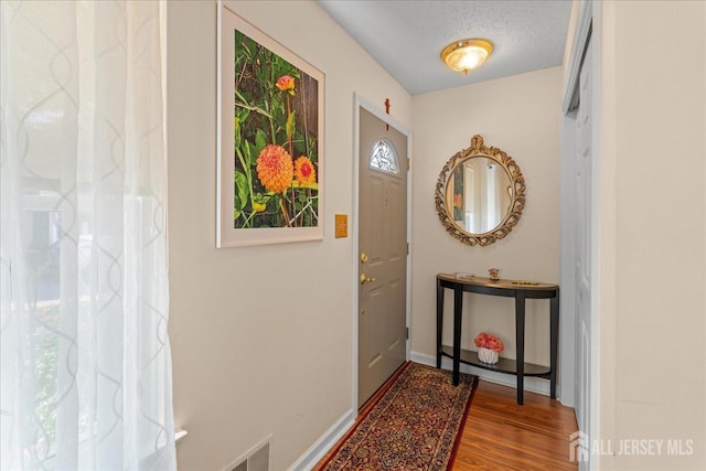 doorway featuring wood-type flooring and a textured ceiling