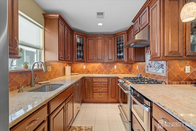 kitchen featuring light stone countertops, sink, range hood, light tile patterned floors, and stainless steel range with gas stovetop