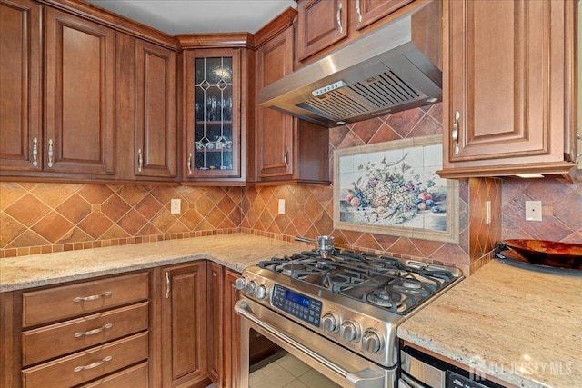 kitchen with light stone countertops, decorative backsplash, ventilation hood, and high end stainless steel range oven