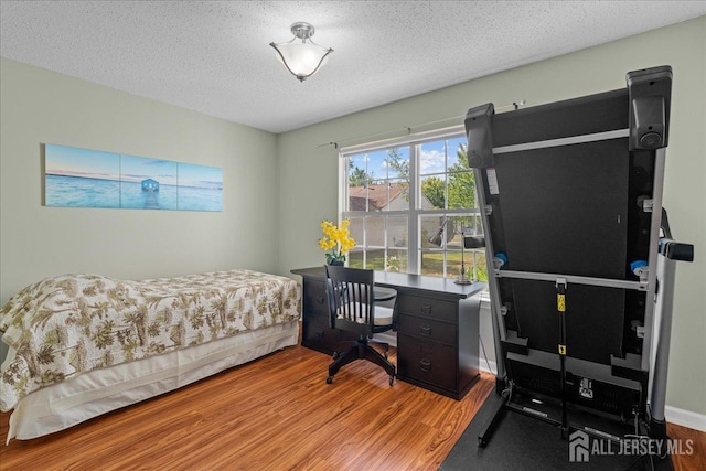 bedroom with a textured ceiling and hardwood / wood-style flooring