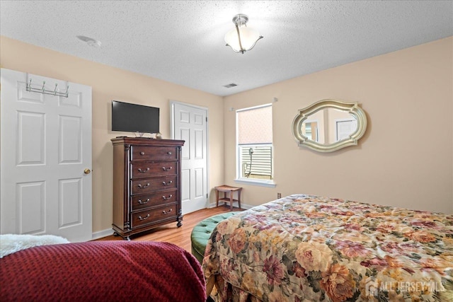 bedroom featuring a textured ceiling and light hardwood / wood-style floors