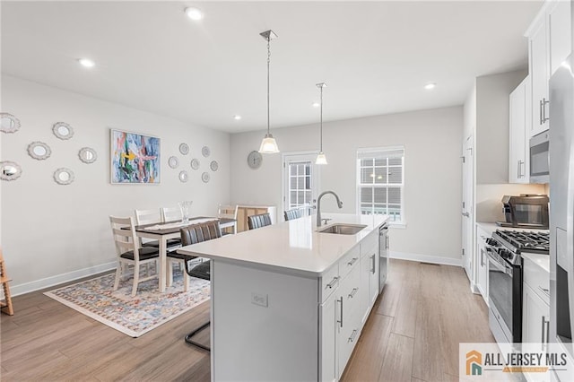 1604 English Ln, Sayreville, NJ 08859 - kitchen with appliances with stainless steel finishes, a kitchen breakfast bar, an island with sink, light countertops, and light wood-style floors
