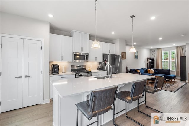 1604 English Ln, Sayreville, NJ 08859 - kitchen with stainless steel appliances, light wood-style flooring, light countertops, open floor plan, and white cabinets