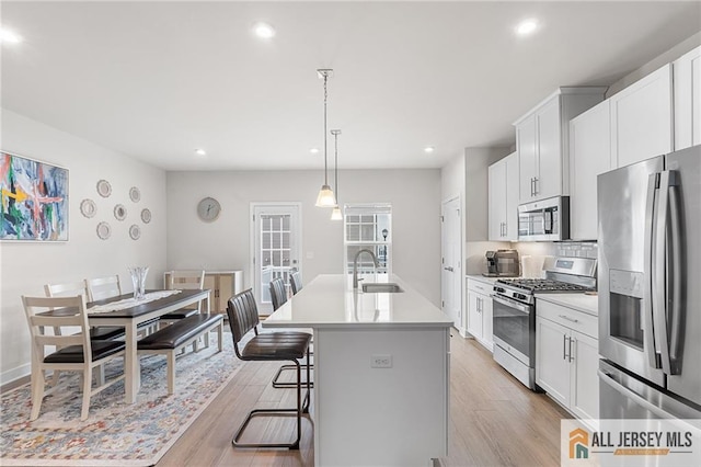 1604 English Ln, Sayreville, NJ 08859 - kitchen featuring appliances with stainless steel finishes, a center island with sink, light wood-style flooring, light countertops, and recessed lighting
