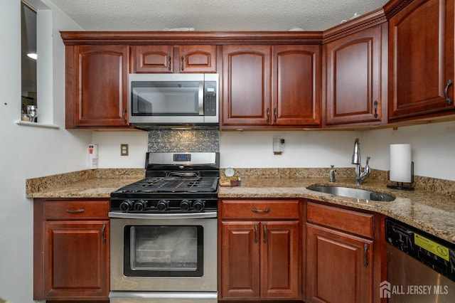 kitchen featuring a textured ceiling, light stone counters, sink, and stainless steel appliances