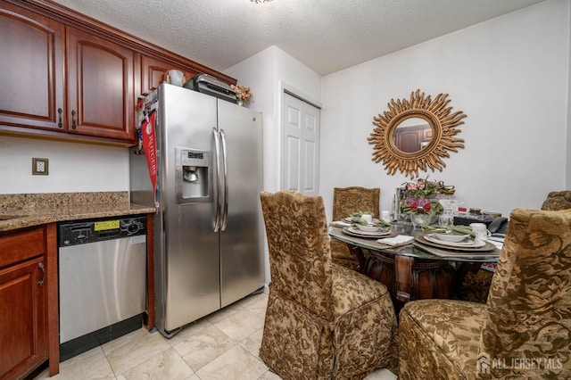 kitchen featuring stone counters, appliances with stainless steel finishes, and a textured ceiling