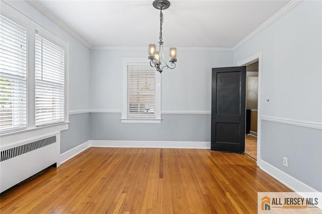 unfurnished dining area with radiator heating unit, a chandelier, light wood-style flooring, ornamental molding, and baseboards