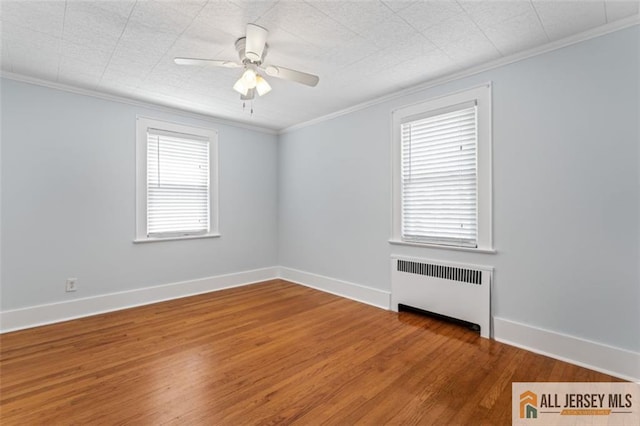 empty room featuring radiator, crown molding, wood finished floors, ceiling fan, and baseboards
