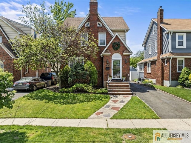view of front facade with a front yard, brick siding, and asphalt driveway