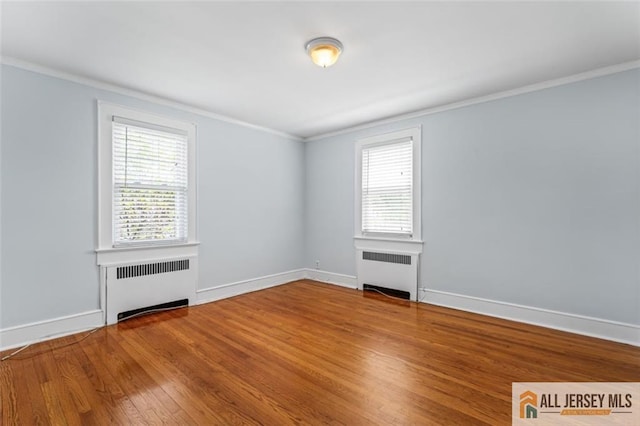 unfurnished room featuring radiator heating unit, crown molding, wood finished floors, and baseboards