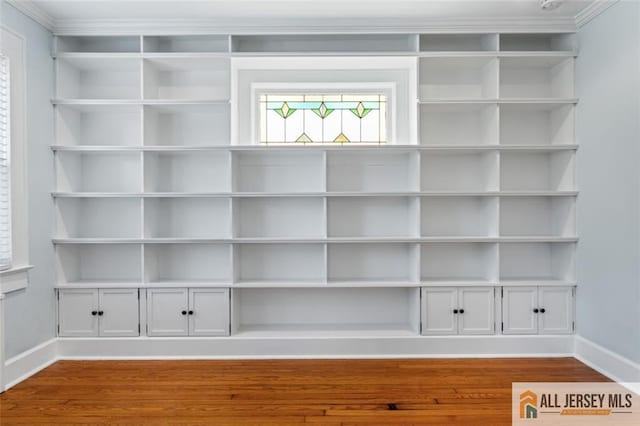 detailed view of baseboards, wood finished floors, and crown molding