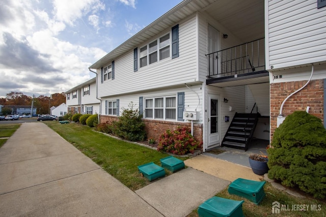 view of property exterior with stairs, brick siding, and a balcony