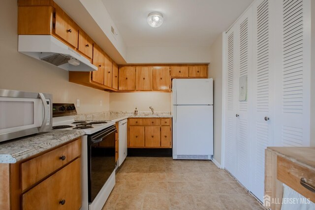 kitchen featuring light stone countertops and white appliances