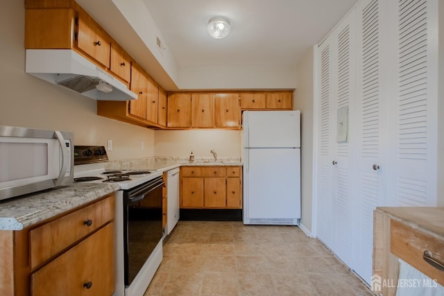 kitchen with white appliances, light tile patterned floors, light stone countertops, visible vents, and under cabinet range hood