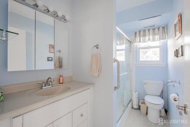 bathroom featuring tile patterned flooring, vanity, toilet, and a shower with shower door