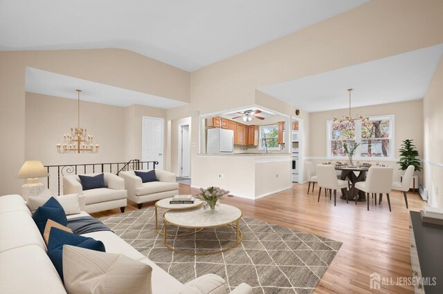 living room featuring an inviting chandelier, lofted ceiling, and light wood-type flooring