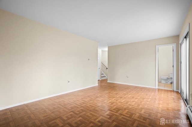 spare room with stairway, a baseboard radiator, and baseboards