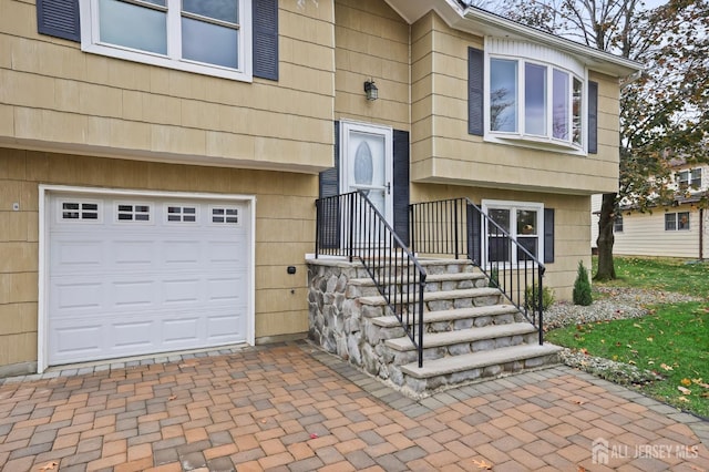 entrance to property featuring decorative driveway and an attached garage