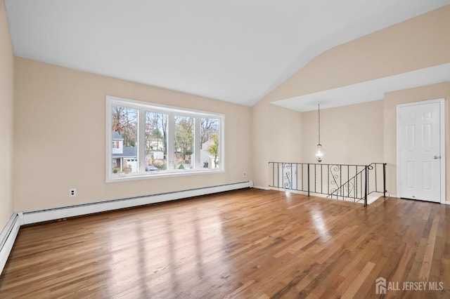 unfurnished room with a baseboard heating unit, vaulted ceiling, and wood finished floors