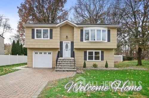 split foyer home with an attached garage, fence, and decorative driveway