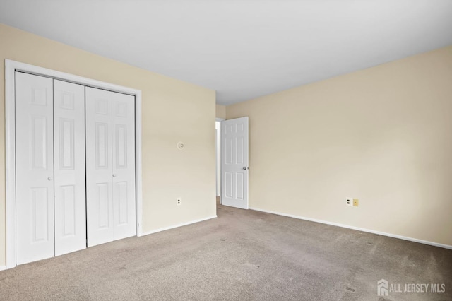 unfurnished bedroom with a closet, carpet, and baseboards