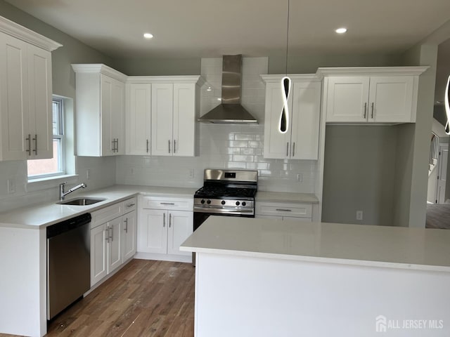 21 Catherine St, Carteret, NJ 07008 - kitchen featuring a sink, wall chimney range hood, white cabinets, appliances with stainless steel finishes, and wood finished floors