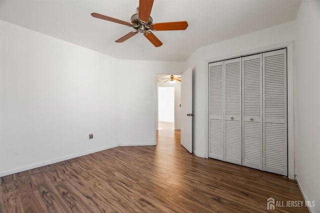 unfurnished bedroom featuring dark hardwood / wood-style flooring, ceiling fan, and a closet