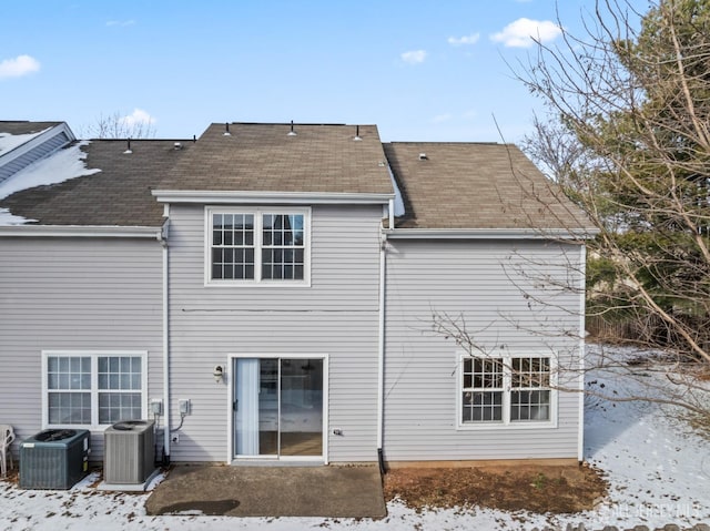 snow covered back of property with central AC