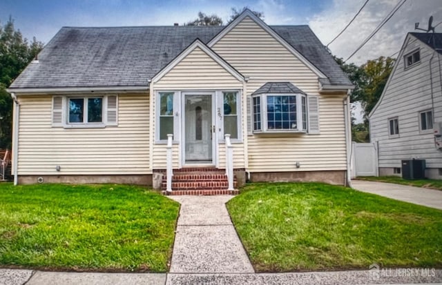 bungalow with a shingled roof, cooling unit, and a front yard