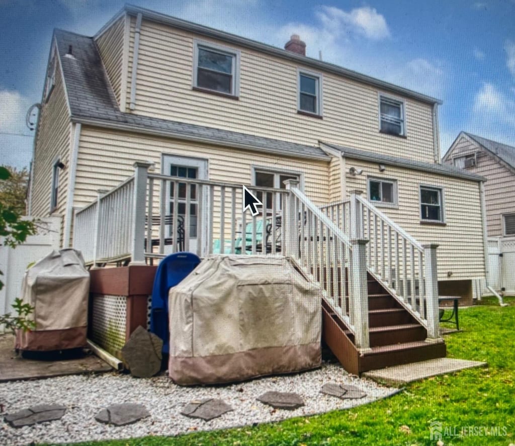 rear view of house with a deck, a yard, and a chimney