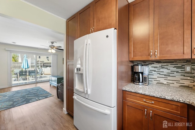kitchen with white refrigerator with ice dispenser, brown cabinetry, and backsplash