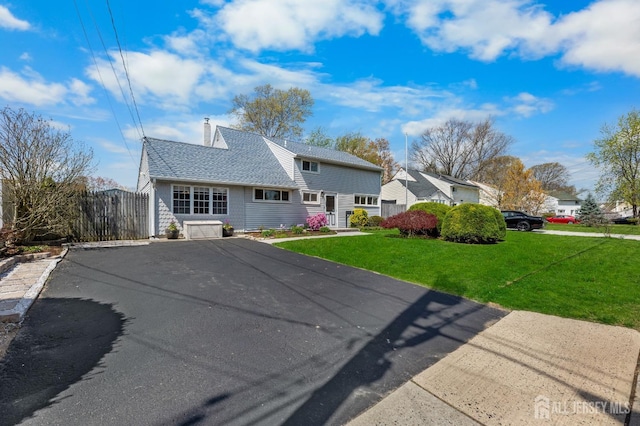 view of front of home featuring driveway, a chimney, and a shingled roof
