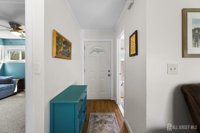 doorway to outside with a ceiling fan, ornamental molding, wood finished floors, and baseboards