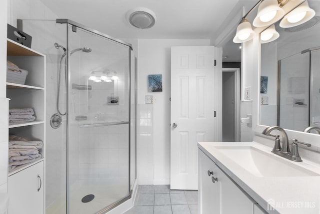 bathroom with a stall shower, tile patterned floors, and vanity